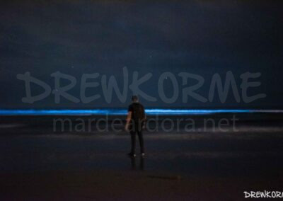 Mar de ardora en la playa de Nemiña (Muxía, Costa da Morte, Galicia) con una persona observando la bioluminiscencia en el mar de noche